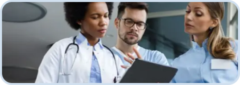 Three doctors in a clinical setting review a tablet together.